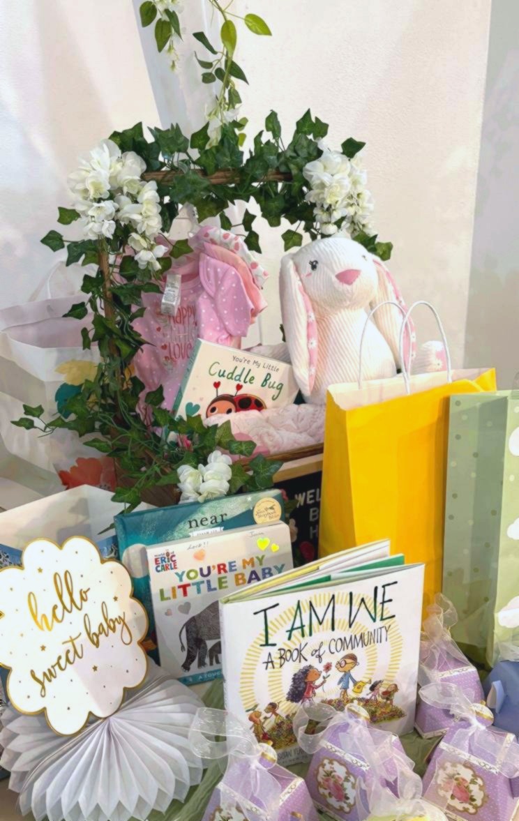 Baby shower gift table display with white bunny plush books and hello sweet baby sign at Carissa Venue