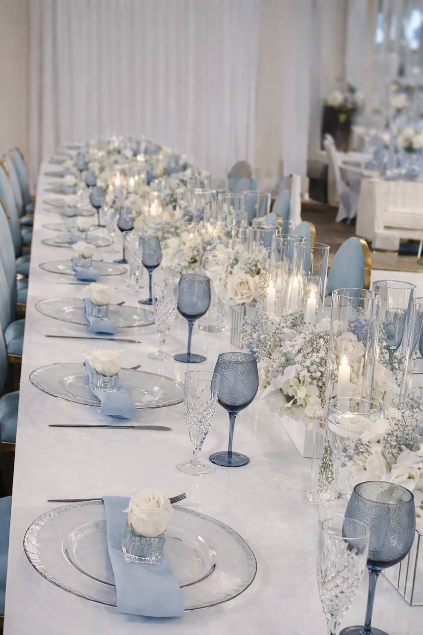 Elegant blue and white tablescape with crystal glasses and candles at Carissa Venue