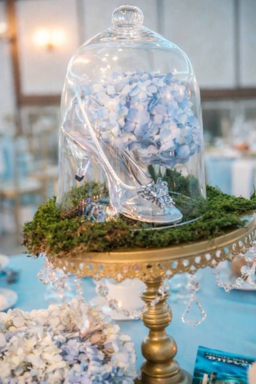 Cinderella glass slipper centerpiece under bell jar on gold stand at Carissa Venue